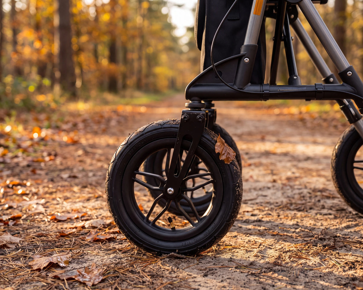 Close-up of the front wheel of the Parvum Rebel in gray with sand and a wet leaf on a forest path.